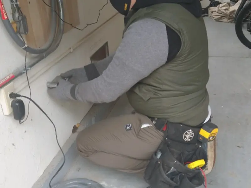 Electrician performing outlet wiring in a Belmar garage